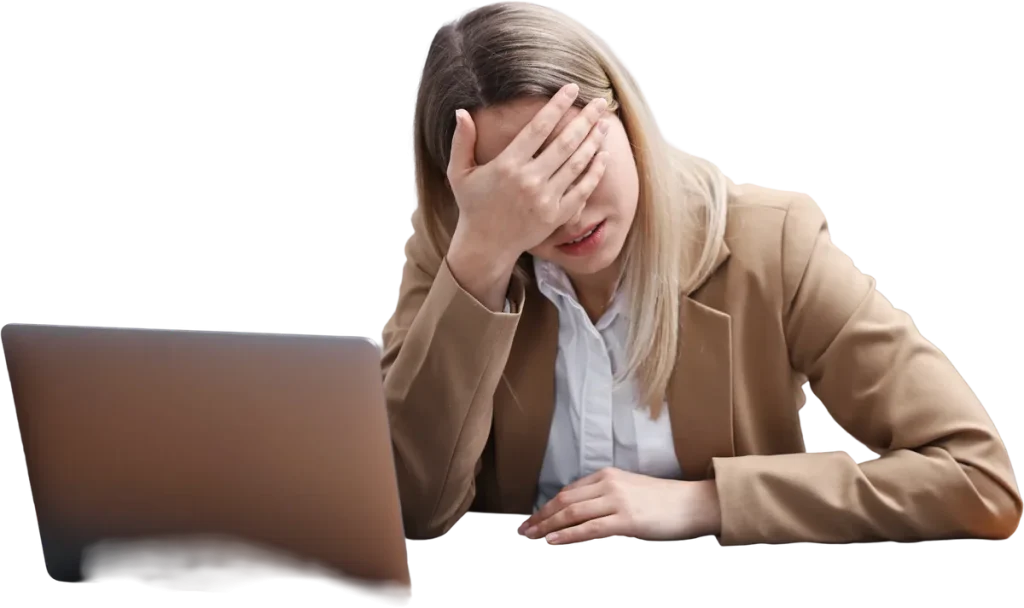 An exhausted employee sitting at a desk with her head in her hand